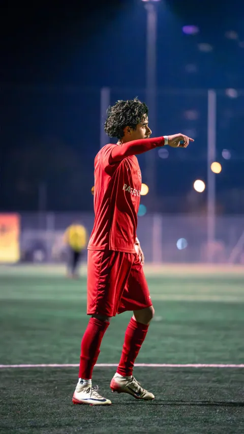 Joueur en rouge donnant des consignes pendant un match en nocturne