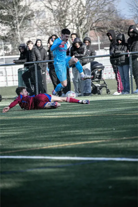 Joueur au sol après un tacle, spectateurs au bord du terrain