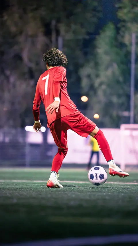 Contrôle du ballon par un joueur en maillot rouge