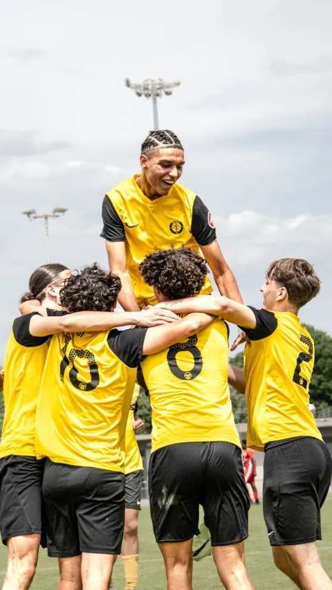 Joueurs en jaune portés en triomphe après un but