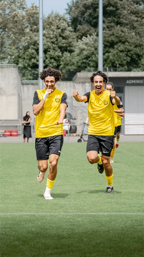 Deux joueurs en jaune célébrant une action en plein match