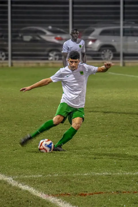 Frappe du ballon par un joueur en maillot blanc