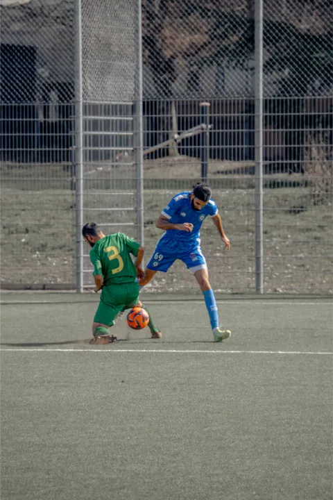 Gardien en vert dégageant le ballon devant un attaquant