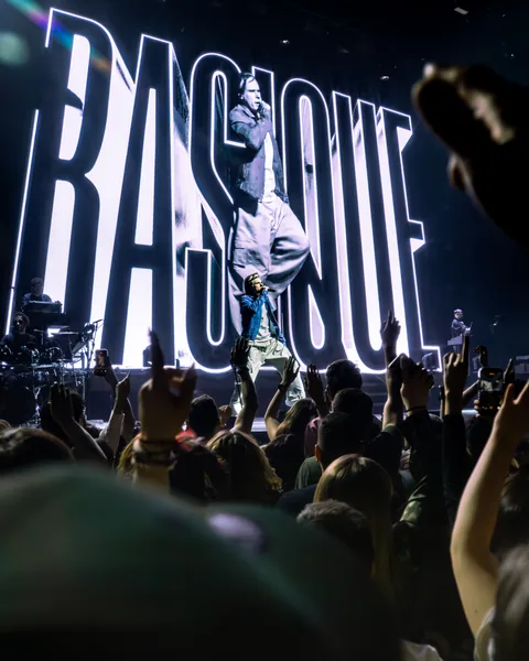 Orelsan sur scène devant des lettres géantes lumineuses, au-dessus de la foule à l'Arena de Genève
