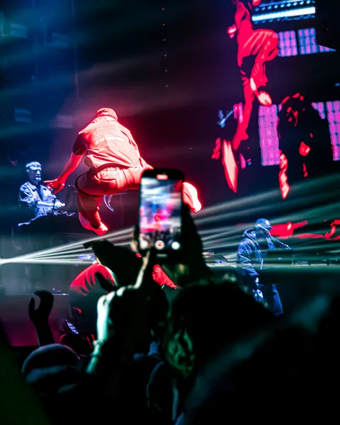 Spectateur filmant au smartphone le show d'Orelsan sur les écrans géants de l'Arena