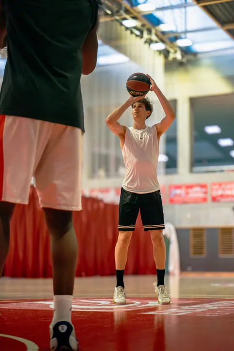 Jeune basketteur au lancer franc dans une salle au sol rouge