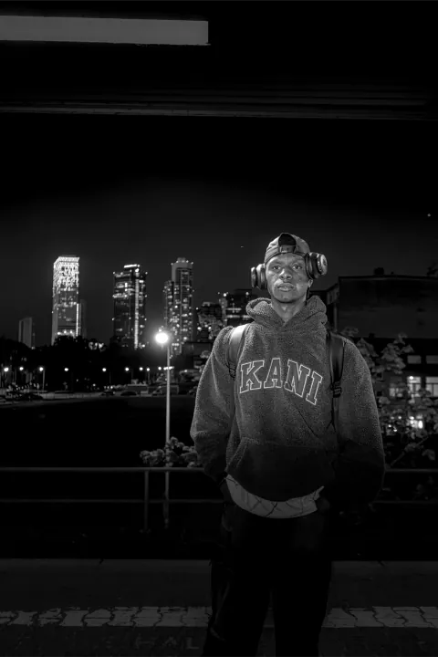 Portrait noir et blanc au casque audio devant une skyline illuminée