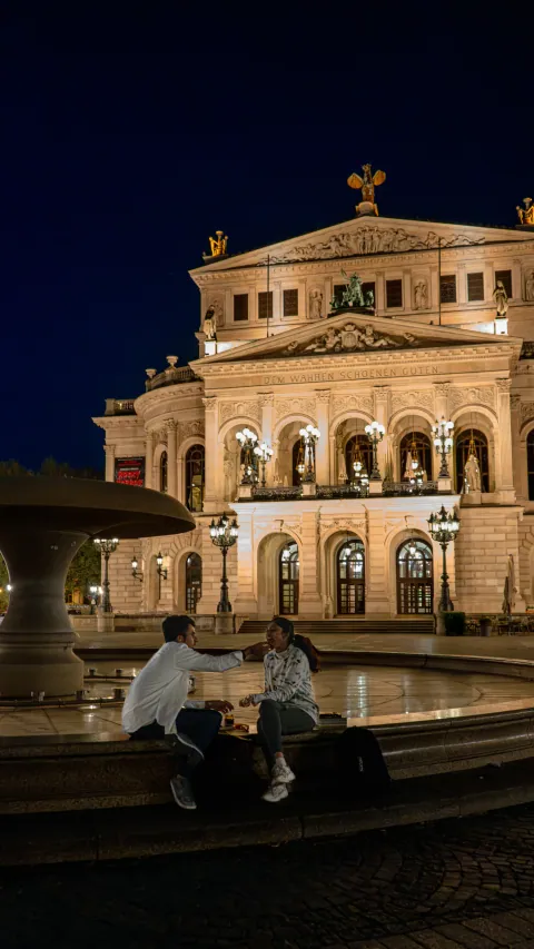 L'Alte Oper de Francfort de nuit, couple assis au bord de la fontaine