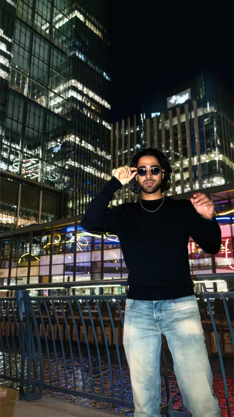 Portrait nocturne aux lunettes de soleil devant les tours de Canary Wharf