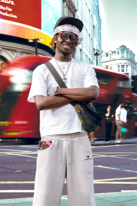 Modèle souriant bras croisés devant deux bus à impériale londoniens